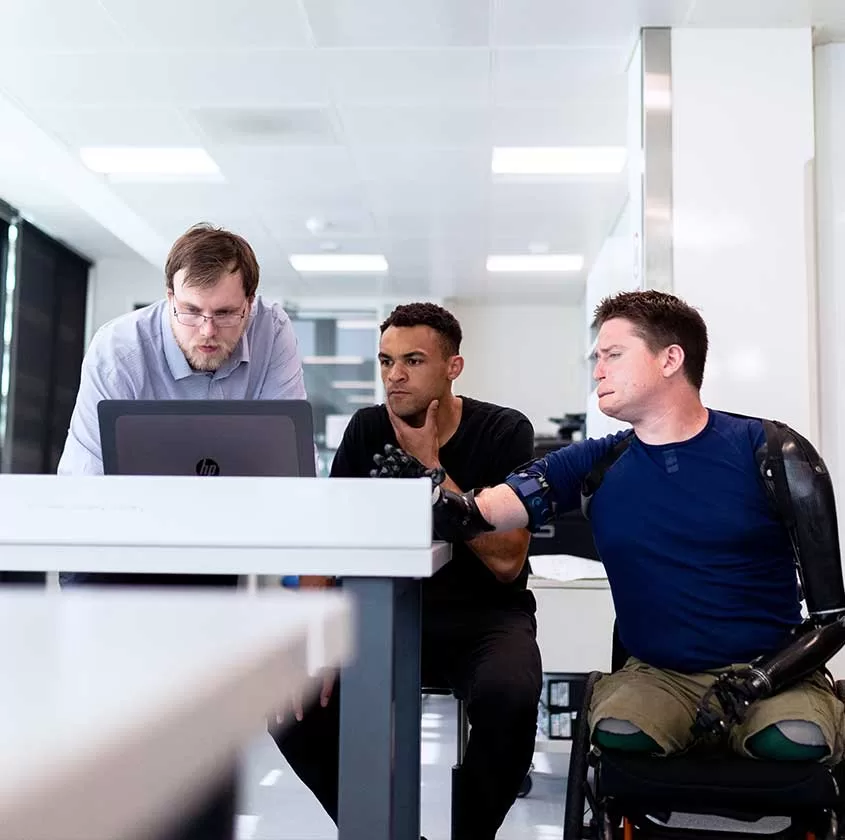 Trois hommes face à un ordinateur, l'air pensif, en train de travailler, dans un bureau.